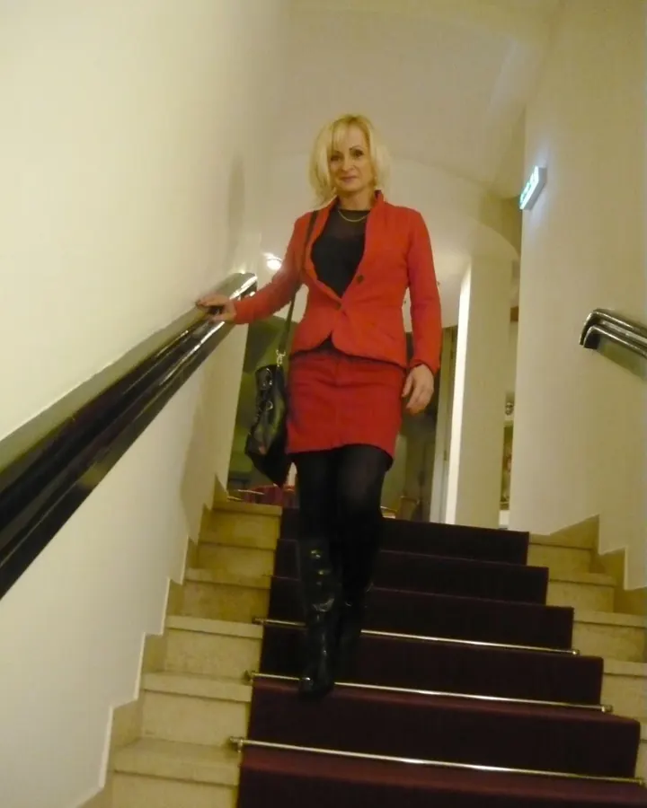 Femme aux cheveux blonds en tenue de sport, posant devant un miroir dans une chambre.