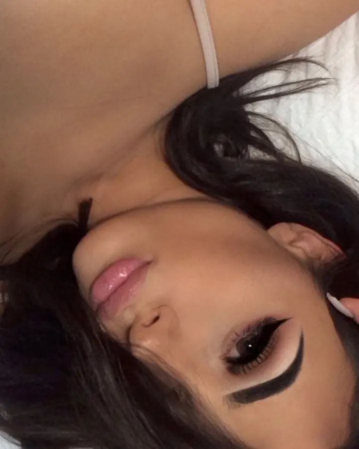 Plan rapproché d'une femme aux cheveux noirs, maquillage prononcé, regardant vers le haut.